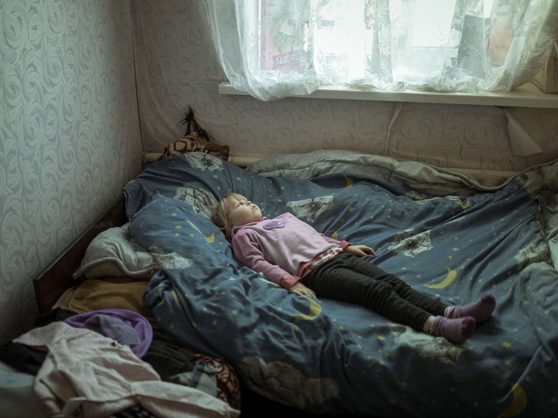 Anhelina (6), who is traumatized and suffers panic attacks after having to flee her village, lies in bed in her new home, in Borshchivka, Ukraine.&nbsp;